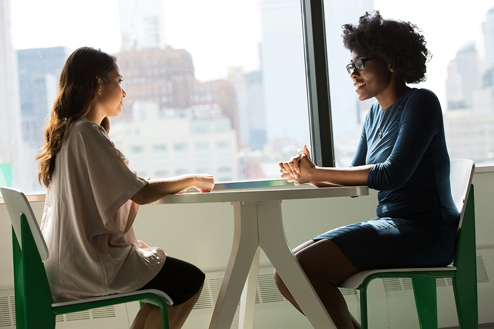 2 women in an office, sat at a desk opposite each other